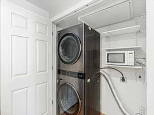 Laundry closet with stacked washer / drying machine and microwave in the kitchen