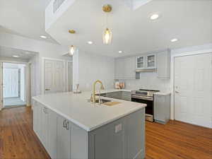 Kitchen with sink, gray cabinetry, hanging light fixtures, stainless steel electric range oven, and dark hardwood / wood-style flooring