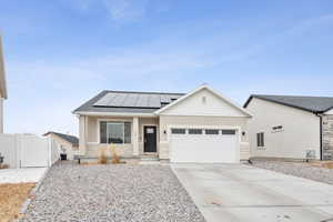 View of front facade featuring a garage, solar panels, and a porch