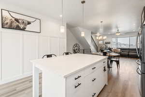 Kitchen with decorative light fixtures, a center island, white cabinets, and light wood-type flooring