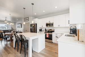 Kitchen with pendant lighting, sink, stainless steel appliances, a center island, and white cabinets