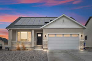 View of front facade featuring a garage and solar panels