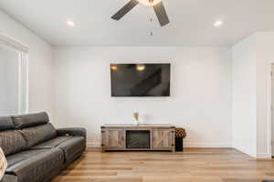 Living room with ceiling fan and light hardwood / wood-style flooring