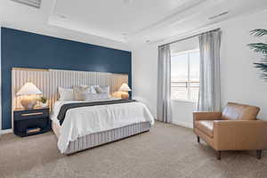 Carpeted bedroom with a tray ceiling