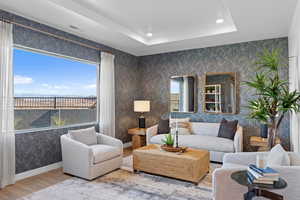 Living room featuring a tray ceiling, plenty of natural light, and wood-type flooring