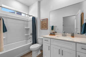 Full bathroom with hardwood / wood-style flooring, vanity, shower / bath combo, and toilet