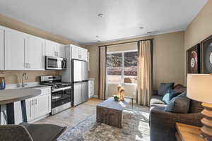 Kitchen with stainless steel appliances, sink, white cabinets, and light hardwood / wood-style flooring