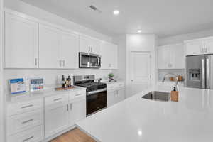 Kitchen with white cabinetry, appliances with stainless steel finishes, and sink