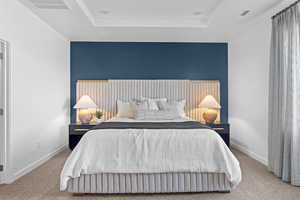 Carpeted bedroom with a tray ceiling