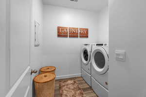 Laundry area with dark wood-type flooring and washing machine and clothes dryer