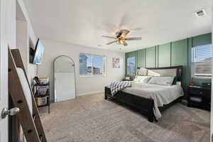 Bedroom with ceiling fan, carpet, and a textured ceiling