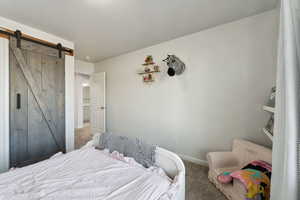 Bedroom with a barn door and carpet floors