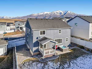 Snow covered rear of property featuring a hot tub and a mountain view