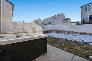 Snow covered patio featuring a hot tub