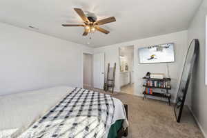 Carpeted bedroom featuring ceiling fan and connected bathroom