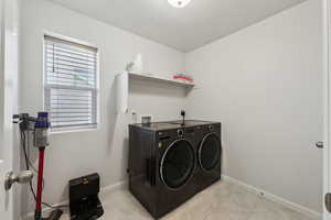 Laundry area with light tile patterned flooring and washer and dryer