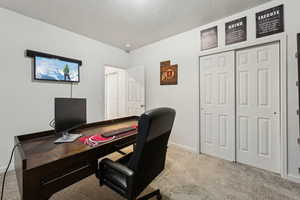 Office with light colored carpet and a textured ceiling