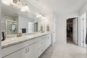 Bathroom featuring tile patterned flooring, vanity, and a shower with shower door