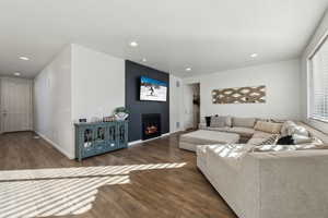 Living room with dark hardwood / wood-style floors and a large fireplace