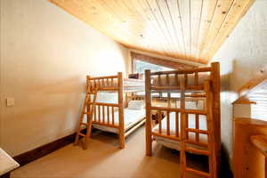 Carpeted bedroom with wood ceiling and lofted ceiling