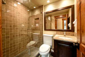 Bathroom with tasteful backsplash, vanity, toilet, and a shower with door