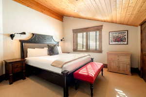 Bedroom with light carpet, vaulted ceiling, and wooden ceiling