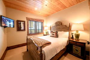 Bedroom with light colored carpet and wood ceiling