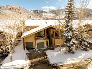 Snow covered property with a mountain view, a garage, and a balcony