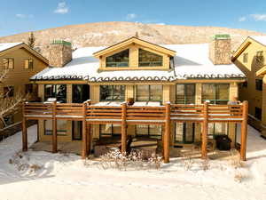 Snow covered house with a patio and a deck with mountain view