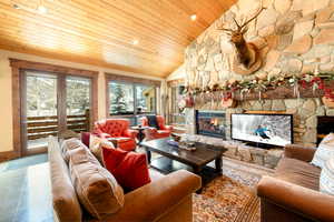 Tiled living room featuring wood ceiling, a stone fireplace, and vaulted ceiling