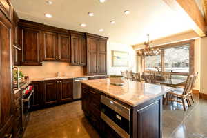 Kitchen featuring pendant lighting, sink, appliances with stainless steel finishes, a kitchen island, and decorative backsplash