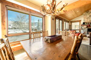 Dining area featuring a mountain view, lofted ceiling, an inviting chandelier, and wood ceiling