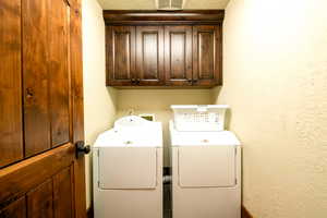 Washroom featuring cabinets and washer and dryer