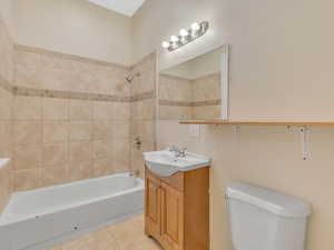 Full bathroom with vanity, tiled shower / bath, tile patterned floors, and toilet