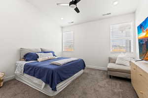 Bedroom featuring multiple windows, dark colored carpet, and ceiling fan