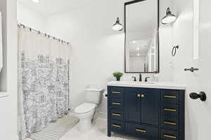 Bathroom with vanity, toilet, and a shower with shower curtain