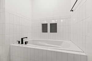 Bathroom featuring tiled bath and tile walls