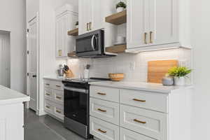 Kitchen with white cabinetry, appliances with stainless steel finishes, and decorative backsplash