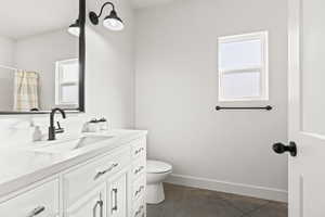 Bathroom featuring vanity, a wealth of natural light, tile patterned floors, and toilet