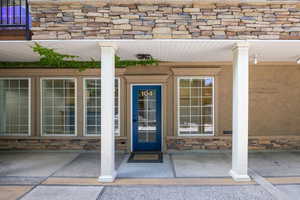 Doorway to property featuring stone siding and a porch