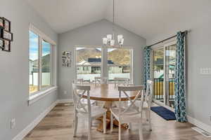 Dining space featuring lofted ceiling, a notable chandelier, and light hardwood / wood-style flooring