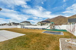 View of yard featuring a playground, a patio, a mountain view, and a storage unit