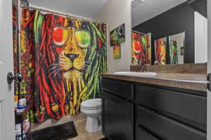 Bathroom with vanity, a textured ceiling, tile patterned floors, and toilet