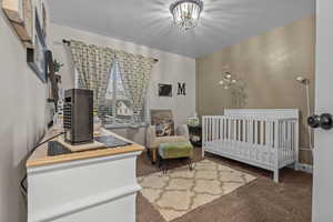 Carpeted bedroom with a crib and a notable chandelier