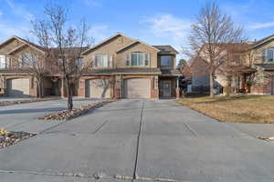 View of property featuring a garage and a front lawn