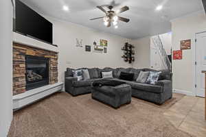 Living room with light tile patterned floors, a fireplace, ornamental molding, and ceiling fan