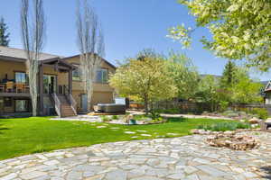 View of yard with a hot tub, a patio, cooling unit, and stairs