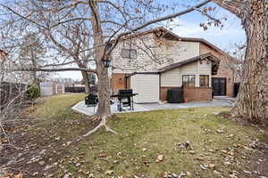 Back of house featuring a storage unit, a patio, and a lawn