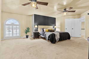 Carpeted bedroom with ceiling fan and a textured ceiling