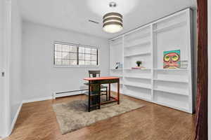 Office space featuring hardwood / wood-style flooring, built in features, and baseboard heating